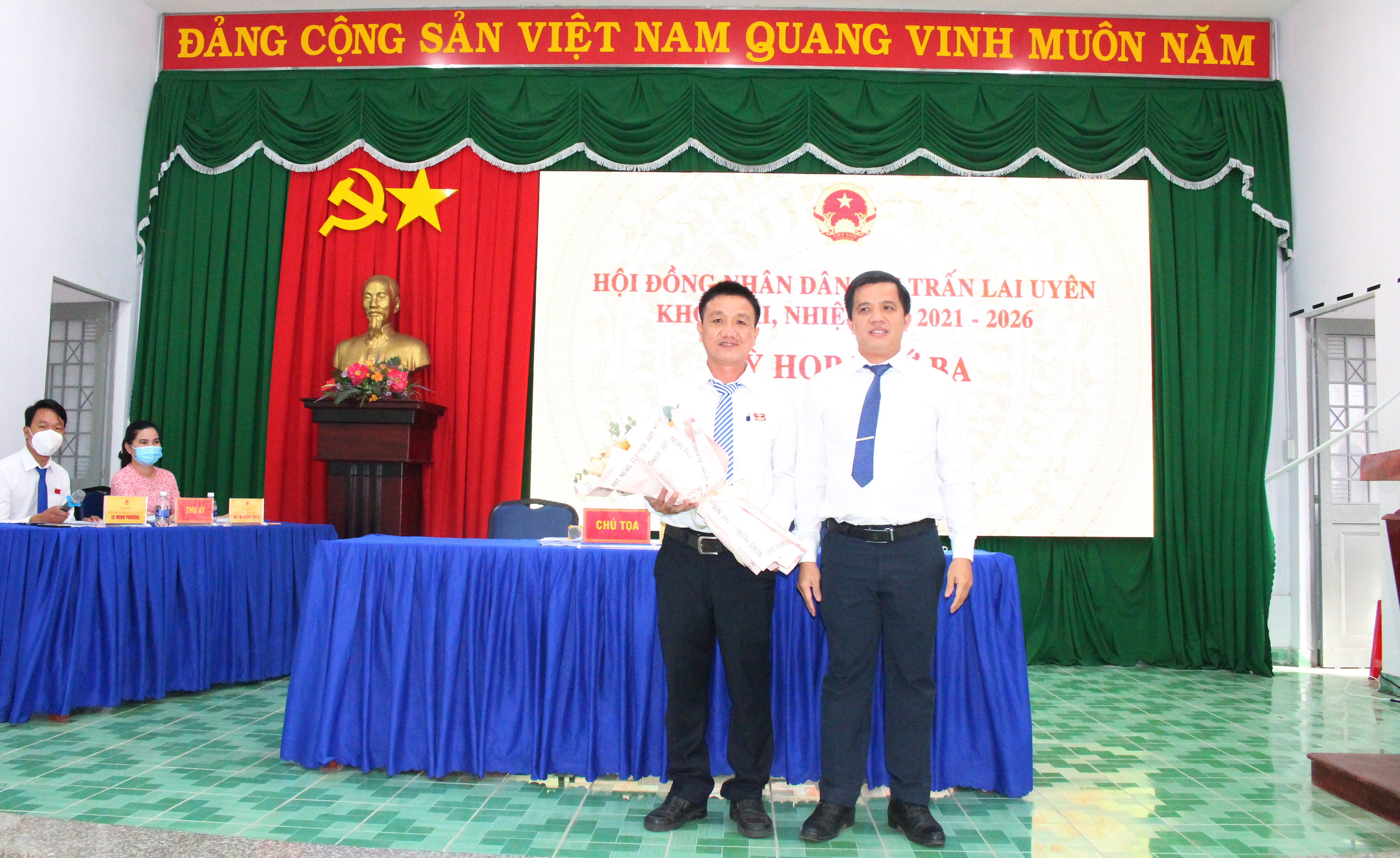 Ông Nguyễn Hữu Luận - Bí thư Đảng ủy thị trấn tặng hoa chức mừng ông Huỳnh Tấn Chung được đại biểu HĐND thị trấn bầu giữ chức Chủ tịch HDdND thị trấn.