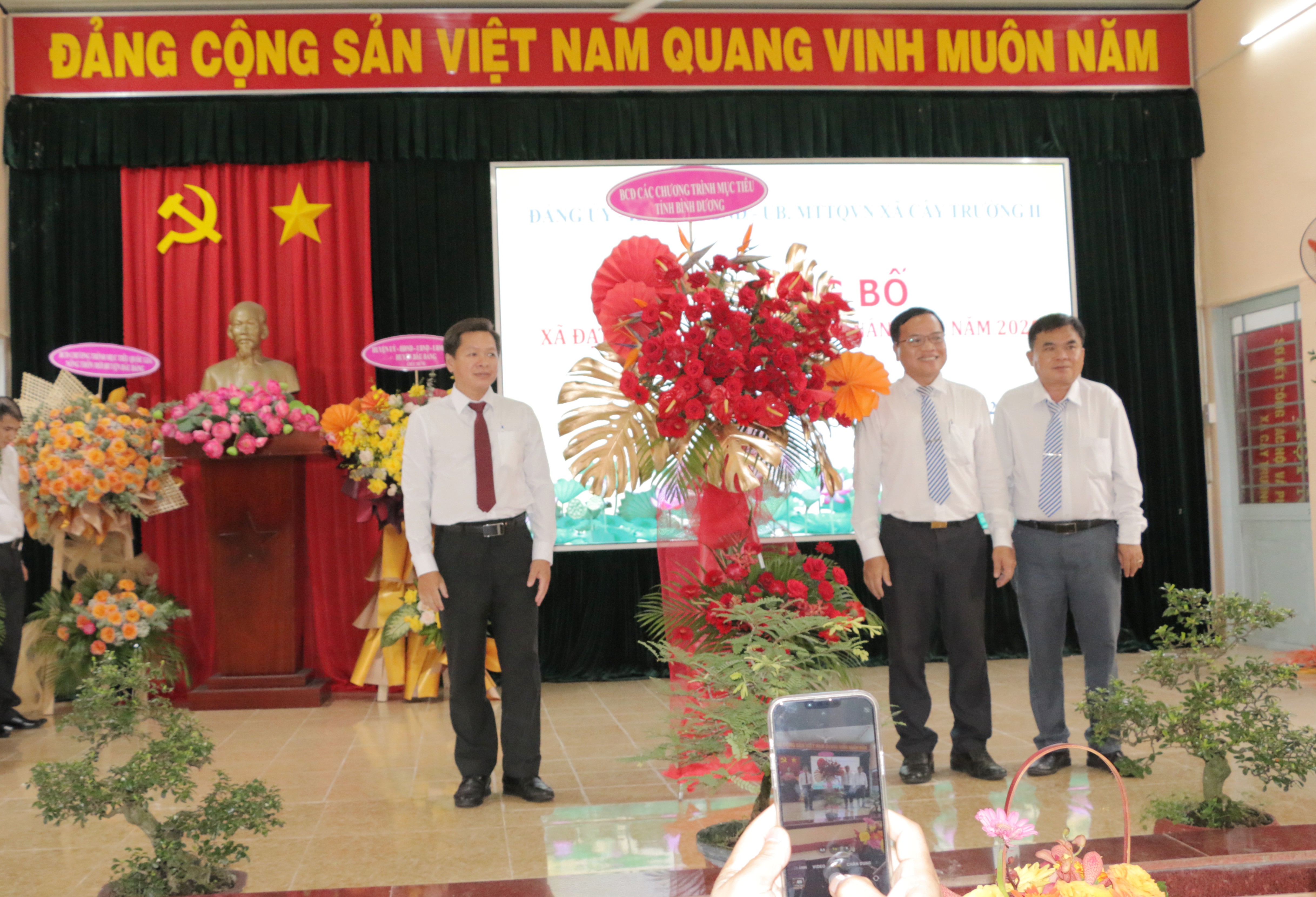 Ông Hồ Thanh Trúc - Phó Giám đốc Sở Nông nghiệp và Phát triển nông thôn tỉnh tặng hoa chúc mừng xã cây trường II đạt chuẩn xã NTM nâng cao.
