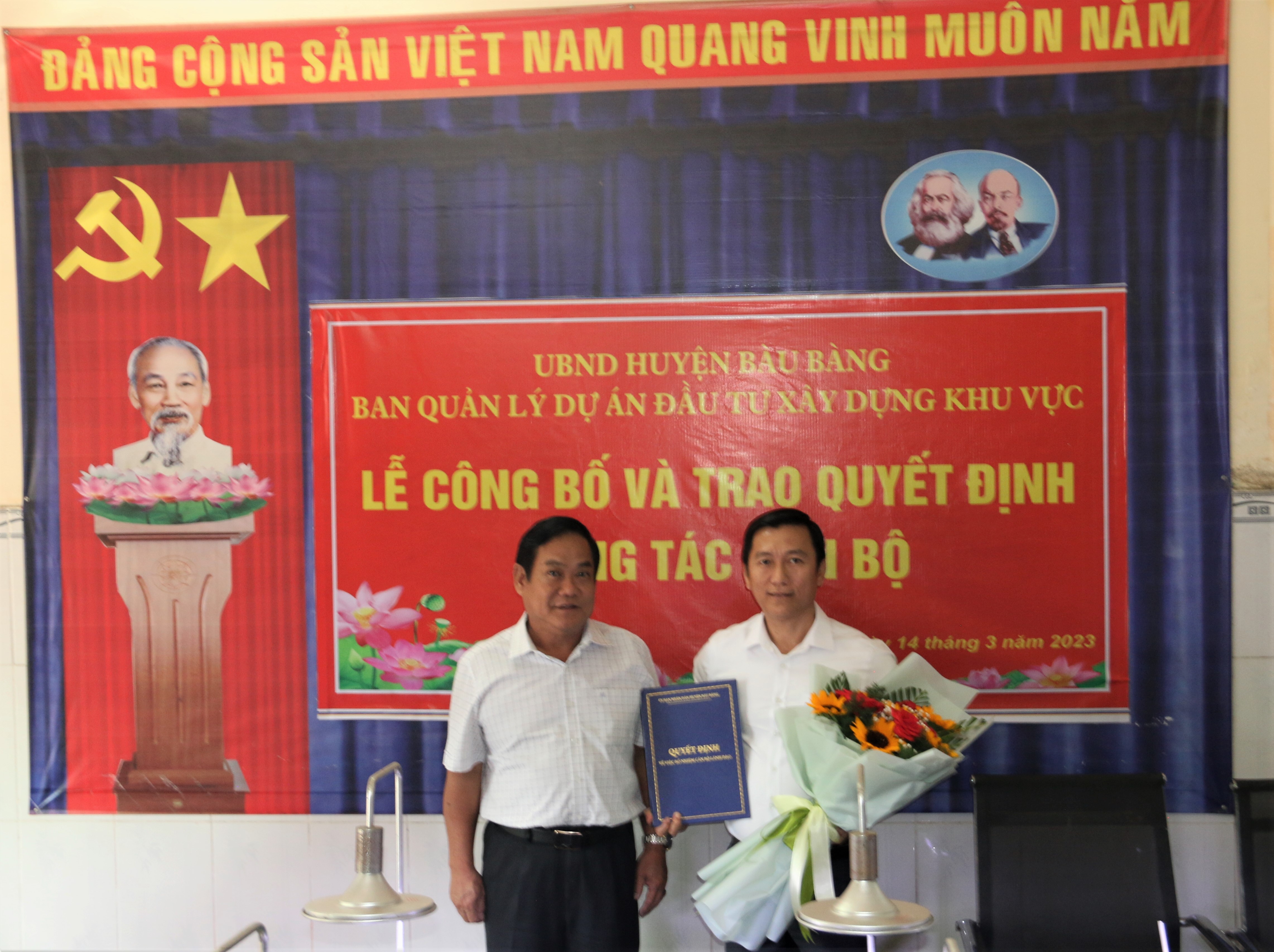 Ông Võ Thành Giàu - Chủ tịch UBND huyện trao Quyết định bổ nhiệm, tặng hoa chúc mừng ông Trần Văn Đông. (Ảnh: Hoàng Tú)